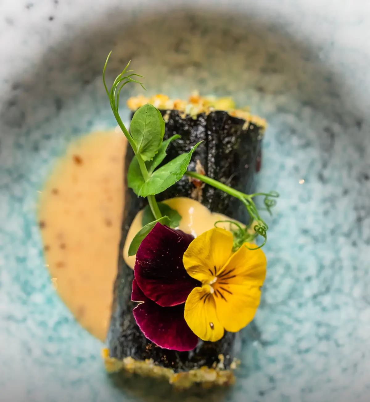 Rolletje met eetbare bloemen op een bedje van saus